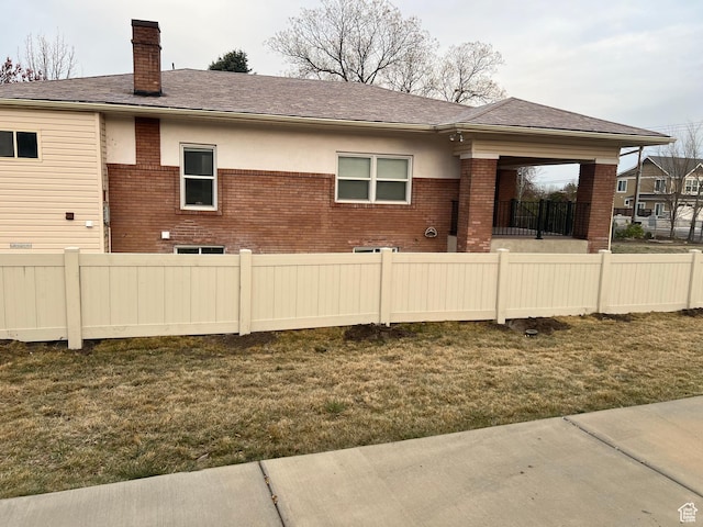 back of property with brick siding, a lawn, fence, and a chimney