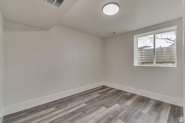 spare room featuring baseboards, visible vents, and wood finished floors