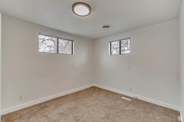 unfurnished room with plenty of natural light, carpet, baseboards, and visible vents