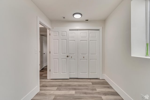 hallway featuring light wood-style flooring and baseboards