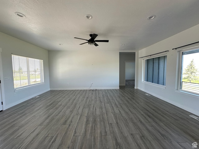 unfurnished living room with a ceiling fan, baseboards, and dark wood finished floors