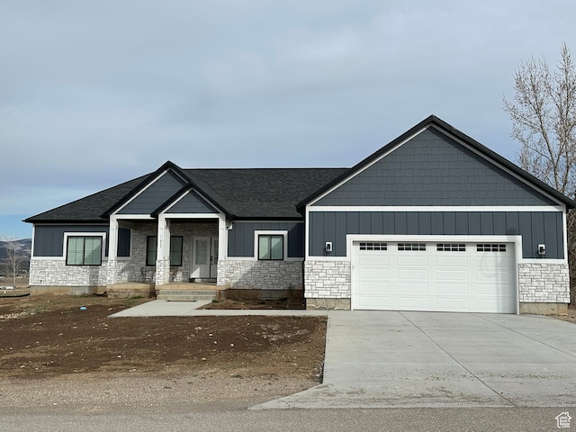 view of front of house featuring a garage, stone siding, and driveway
