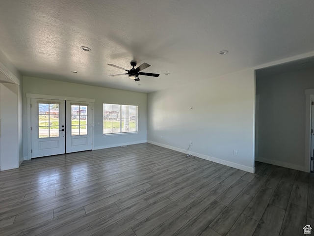 unfurnished living room featuring dark wood finished floors, baseboards, a ceiling fan, and plenty of natural light