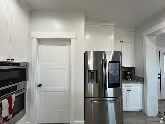 kitchen featuring light stone counters, appliances with stainless steel finishes, decorative backsplash, and white cabinetry