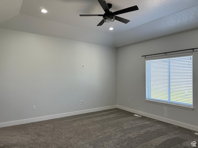 empty room with ceiling fan, dark carpet, vaulted ceiling, and baseboards
