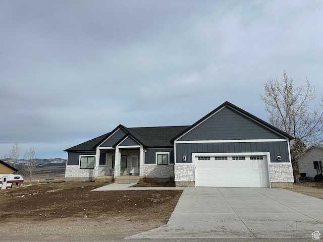 view of front facade featuring stone siding, board and batten siding, concrete driveway, and an attached garage