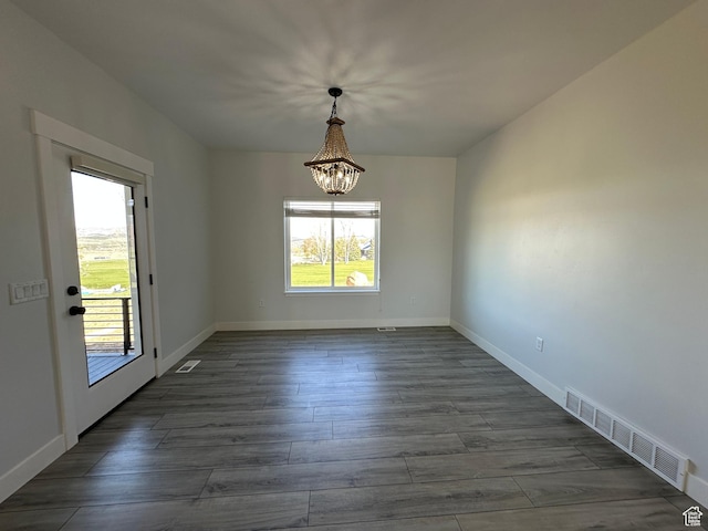 unfurnished dining area with a chandelier, visible vents, dark wood finished floors, and baseboards