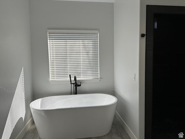 bathroom featuring baseboards and a freestanding tub