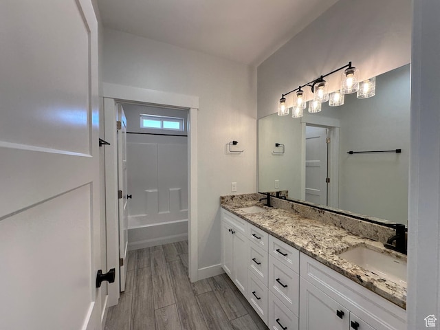 bathroom with double vanity, a sink, wood finished floors, and baseboards