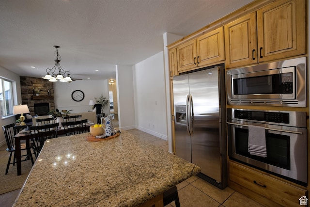 406 N 1420 E, Provo, UT 84606 - kitchen featuring light stone counters, a fireplace, open floor plan, light tile patterned floors, and stainless steel appliances