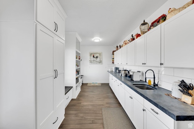 kitchen featuring a sink, open shelves, dark countertops, and dark wood-style floors