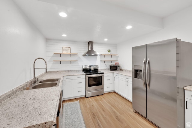 kitchen featuring open shelves, light wood-type flooring, stainless steel appliances, wall chimney exhaust hood, and a sink