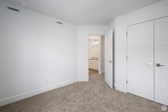 unfurnished bedroom featuring light carpet, visible vents, a closet, and baseboards