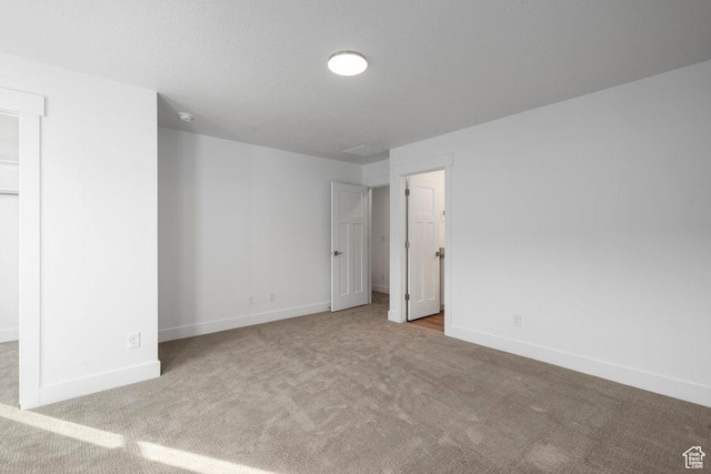 spare room featuring carpet flooring, a textured ceiling, and baseboards