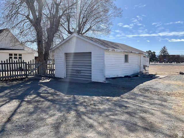 detached garage featuring driveway and fence