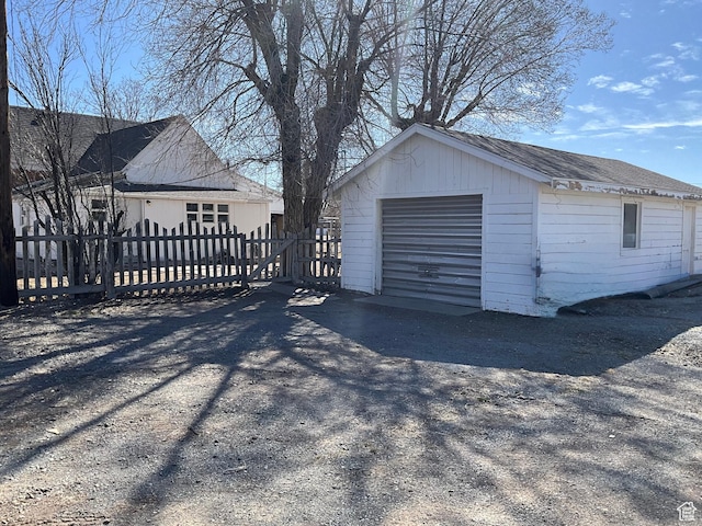 detached garage featuring fence and driveway