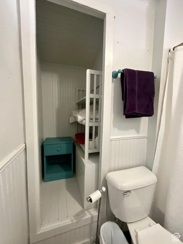 full bath with wainscoting, toilet, and a shower with shower curtain
