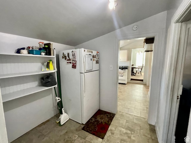 kitchen featuring lofted ceiling and freestanding refrigerator