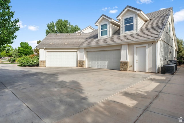 2917 S Old Farm Rd, Washington, UT 84780 - view of front facade featuring a garage, central air condition unit, stone siding, and concrete driveway