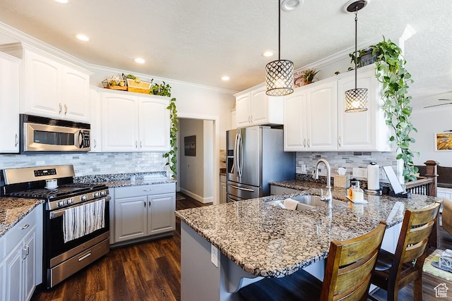 kitchen with dark stone countertops, a peninsula, a sink, stainless steel appliances, and a kitchen breakfast bar