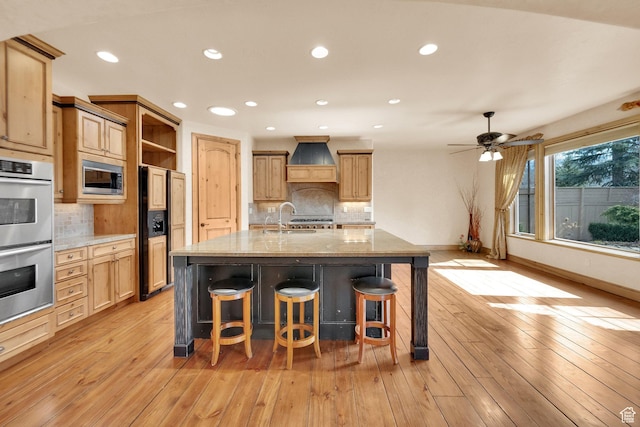 kitchen featuring open shelves, custom range hood, built in appliances, light wood finished floors, and a sink