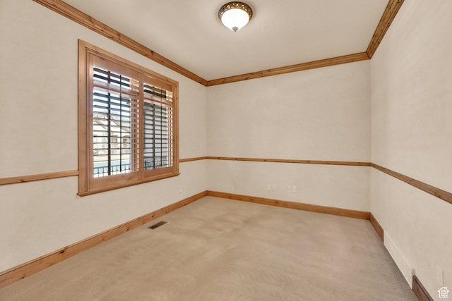 spare room featuring baseboards, visible vents, ornamental molding, and carpet flooring