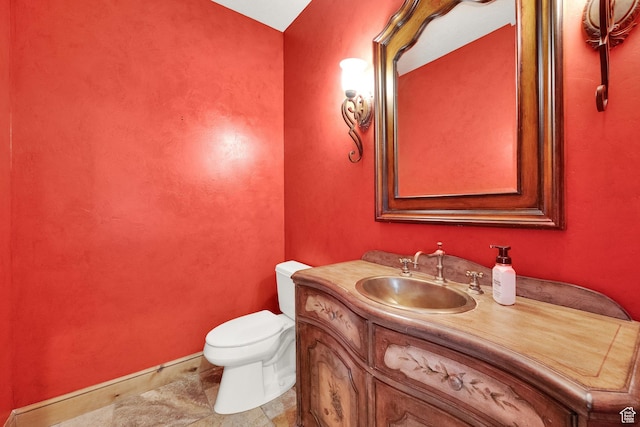 half bathroom featuring vanity, toilet, and baseboards