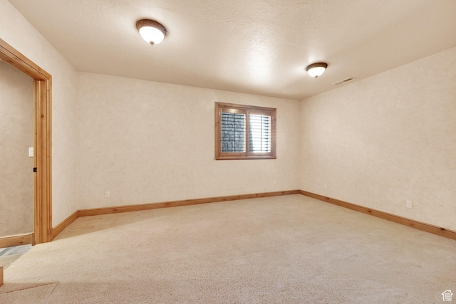 empty room with light colored carpet, visible vents, and baseboards