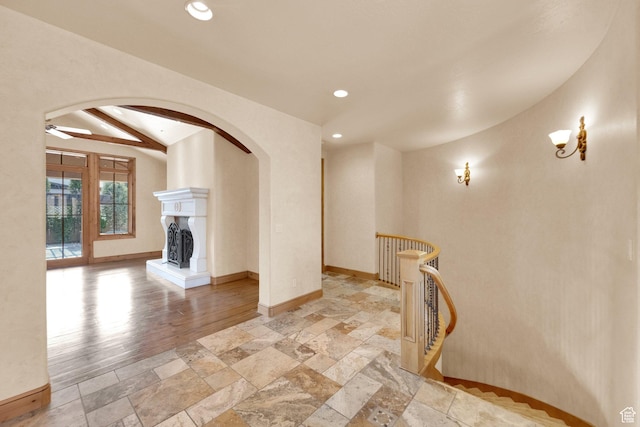 unfurnished living room featuring arched walkways, stone tile floors, and baseboards