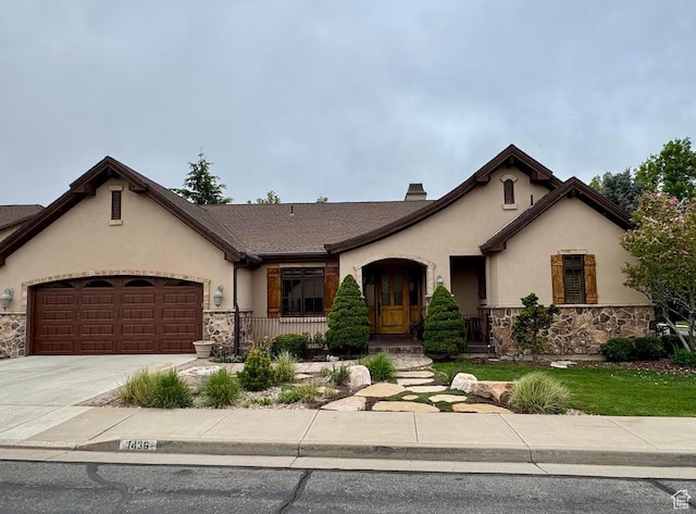 view of front of house with stucco siding, driveway, stone siding, and a garage