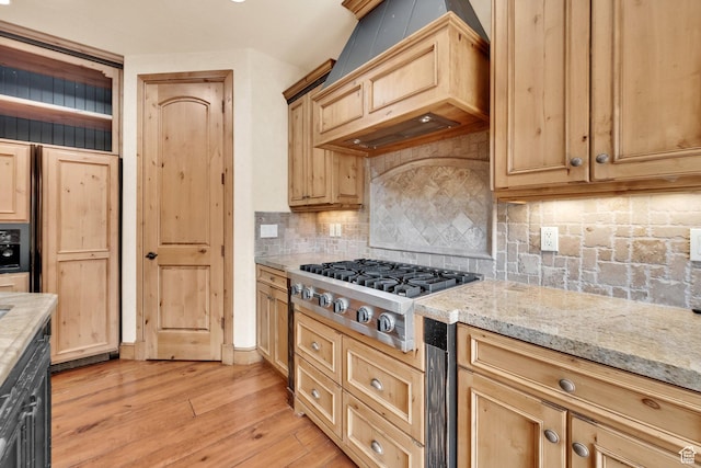 kitchen featuring stainless steel gas cooktop, light brown cabinets, light stone counters, light wood-style floors, and backsplash