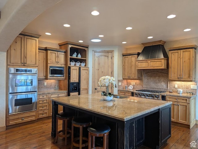 kitchen featuring light stone countertops, open shelves, built in appliances, a sink, and premium range hood