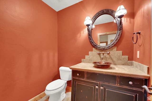 half bathroom with baseboards, toilet, and vanity