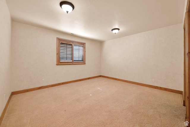 carpeted empty room featuring baseboards