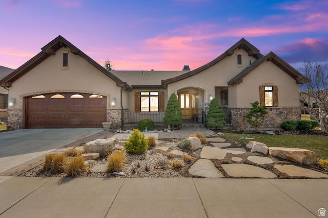 view of front of property with concrete driveway, stucco siding, an attached garage, and stone siding
