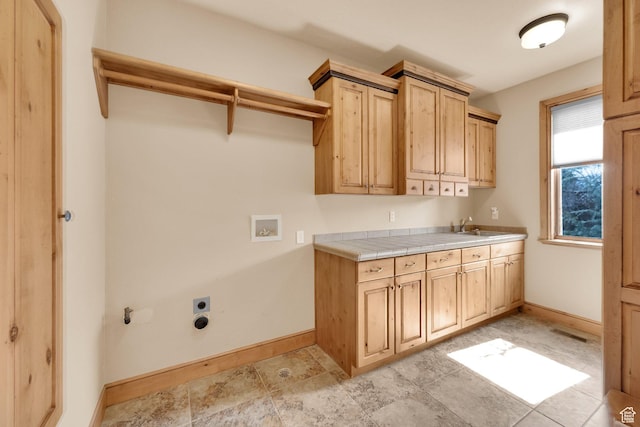 clothes washing area featuring hookup for an electric dryer, washer hookup, a sink, baseboards, and cabinet space