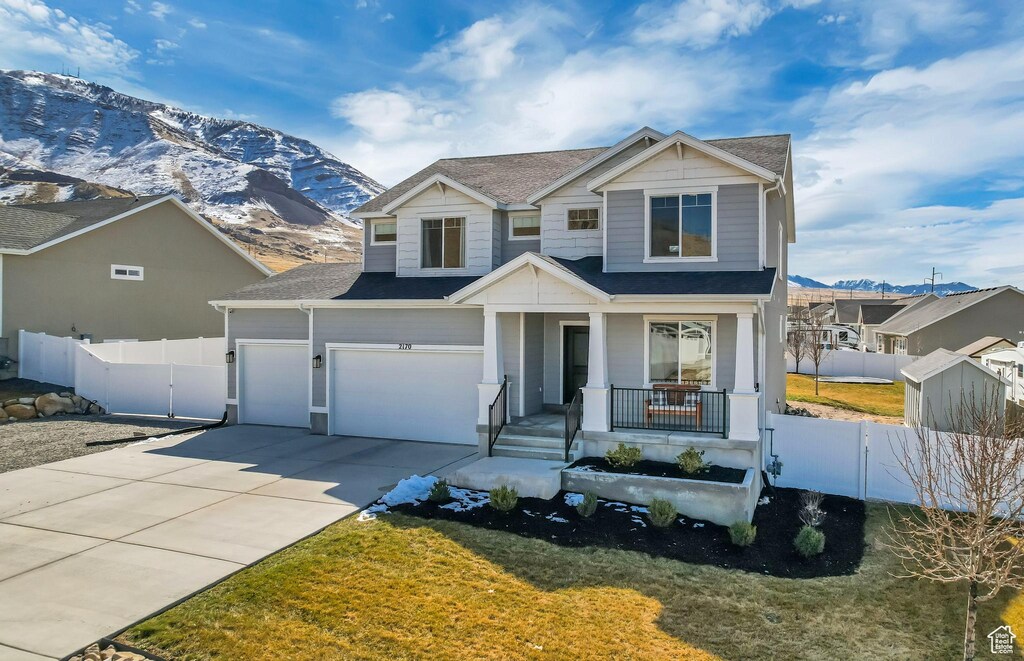 view of front of property featuring an attached garage, fence, covered porch, driveway, and a mountain view