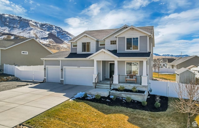 view of front of property featuring an attached garage, fence, covered porch, driveway, and a mountain view