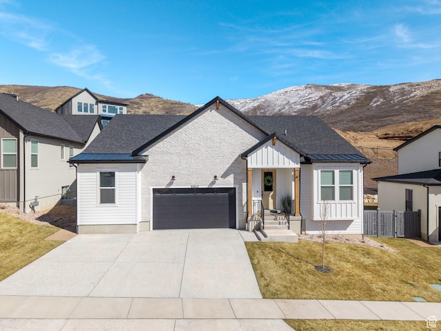 view of front facade featuring a mountain view, an attached garage, a front yard, and fence