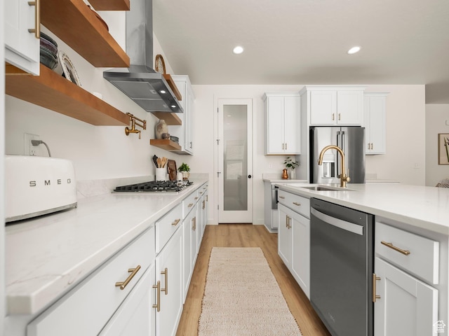 kitchen featuring light wood-style flooring, range hood, stainless steel appliances, white cabinets, and light countertops