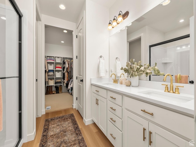 full bath with a shower stall, wood finished floors, and a sink