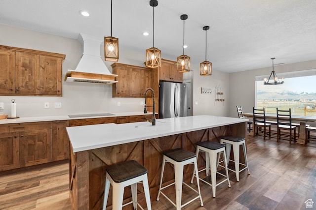 1984 S 4300 W, Ogden, UT 84401 - kitchen featuring premium range hood, freestanding refrigerator, brown cabinetry, black electric cooktop, and wood finished floors
