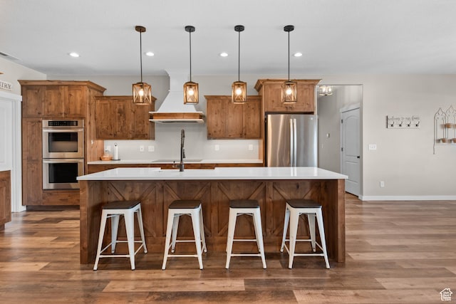 1984 S 4300 W, Ogden, UT 84401 - kitchen featuring brown cabinetry, premium range hood, appliances with stainless steel finishes, and wood finished floors