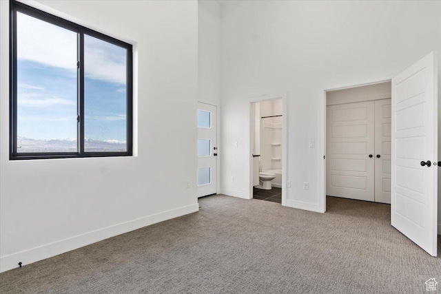 unfurnished bedroom with carpet flooring, connected bathroom, and baseboards