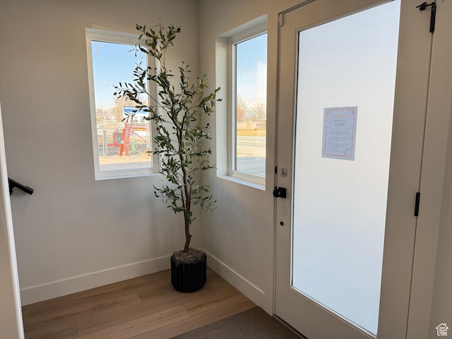 doorway featuring baseboards and light wood finished floors