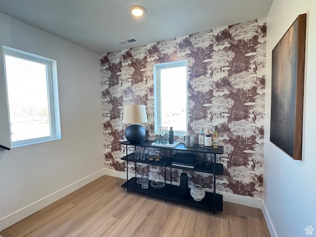 home office featuring visible vents, baseboards, wood finished floors, and wallpapered walls