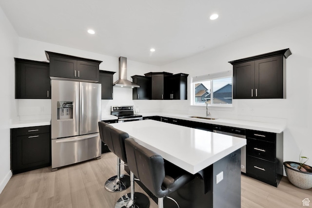 1373 E Bell Buoy Way S, Eagle Mountain, UT 84005 - kitchen with light wood finished floors, a kitchen island, a sink, stainless steel appliances, and wall chimney range hood
