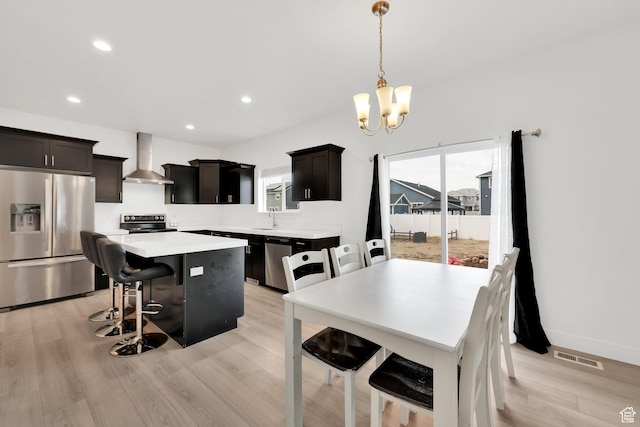 1373 E Bell Buoy Way S, Eagle Mountain, UT 84005 - kitchen featuring a center island, a breakfast bar area, appliances with stainless steel finishes, light wood-style floors, and wall chimney exhaust hood