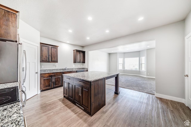 8052 N Rock Creek Cove Ln, Eagle Mountain, UT 84005 - kitchen featuring light wood-style flooring, a center island, recessed lighting, light stone countertops, and dark brown cabinets