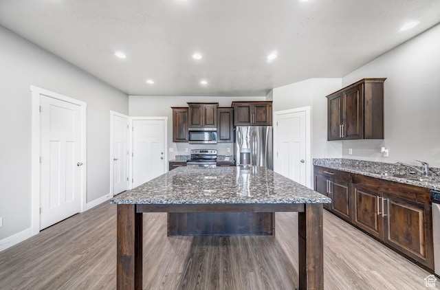 8052 N Rock Creek Cove Ln, Eagle Mountain, UT 84005 - kitchen with dark stone counters, a sink, stainless steel appliances, dark brown cabinets, and a kitchen bar